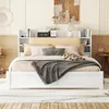 A white bed with a headboard featuring shelves, set up in a bedroom with decorative items and a painting above. Náhled obrázku produktu
