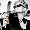 A woman is holding a perfume bottle and spraying it. Voir les images du produit