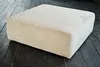 A cream-colored corduroy ottoman sits on a dark wooden floor. Produktbild-Vorschau