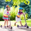 Two children are riding scooters in a park. Náhľad obrázku produktu