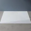 A white shower tray with a textured surface and a drain in the center, placed on a gray floor against a dark gray wall. Anteprima dell’immagine prodotto