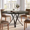 A round dining table with chairs in a well-lit room with large windows. Anteprima dell’immagine prodotto