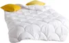 A white comforter with a quilted pattern and two yellow pillows on top, set against a white background. Produktbild-Vorschau