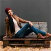 A woman is sitting on a pallet bench with cushions, surrounded by fallen leaves. Náhled obrázku produktu