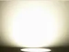 A bright light source illuminates a white wall from below, with a white circular object visible at the bottom. Náhled obrázku produktu