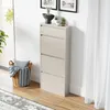 A tall, narrow shoe cabinet with four flip-down drawers stands against a white wall. A woven basket with pillows and blankets sits to the left of the cabinet, and a rug is visible on the wooden floor. Voir les images du produit