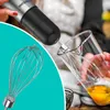 A hand holding a hand blender with a whisk attachment, about to mix eggs in a glass beaker. Anteprima dell’immagine prodotto