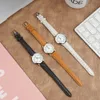Three women's watches with different colored leather straps laid out on a textured brown surface. Produktbild-Vorschau