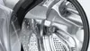Close-up of the inside of a washing machine drum, showing the stainless steel material and perforations. Produktbild-Vorschau