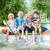 Four children are sitting on a colorful oval nest swing in a park setting. Anteprima dell’immagine prodotto