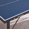A close-up view of a blue mini-table tennis table with white lines, showing the brand name 'sweeek.' and a metal hinge. Produktbild-Vorschau
