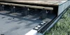 A close-up view of a deck substructure, showing adjustable pedestals supporting wooden joists and decking. Produktbild-Vorschau