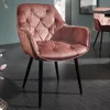 A close-up shot of a tufted velvet armchair with black metal legs, placed on a dark wooden floor. Produktbild-Vorschau