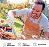 A man is grilling outdoors, wearing heat-resistant gloves and using tongs to turn food on the grill. There are other people and food in the background. Produktbild-Vorschau