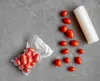 Cherry tomatoes are shown vacuum-sealed in a bag and scattered around a roll of vacuum sealing film on a gray textured surface. Produktbild-Vorschau