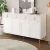 A white sideboard with gold handles and legs, placed in a room with a plant and artwork. Produktbild-Vorschau