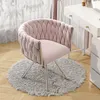 A pink velvet chair with silver legs sits on a fluffy gray rug next to a white vanity table. Produktbild-Vorschau