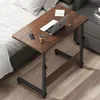 A mobile C-shaped table with a laptop, phone, and coffee cup on it, placed next to a bed.