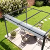 A patio with a pergola, table, and chairs, set in a garden. Voir les images du produit