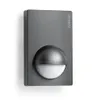 A dark grey motion sensor is mounted on a white wall. Podgląd zdjęcia produktu