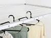 A close-up view of a ceiling-mounted clothes drying rack with clothes hanging on it. Voir les images du produit