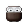 A brown leather case for AirPods (3rd gen) with the case open, revealing the white AirPods inside. A small green light is visible on the front of the case. Podgląd zdjęcia produktu