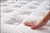 A hand is shown pressing down on a white mattress with a textured surface. The text "THERMO CONTROL" is visible on the mattress. Produktbild-Vorschau