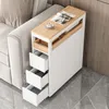 A narrow cabinet with drawers and shelves is placed next to a sofa, with a cup of coffee and magazines on top. Produktbild-Vorschau