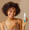 A woman is holding a bottle of Odaban Antitranspirant Deodorant Spray and pointing to it. Produktbild-Vorschau