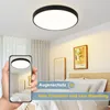 A bedroom scene with a ceiling light and a hand holding a smartphone showing the ceiling light. Produktbild-Vorschau