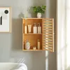 A wooden bathroom cabinet mounted on a gray wall, filled with various toiletries. Anteprima dell’immagine prodotto