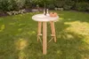 A wooden high table with a bottle of wine and two glasses on it, placed on a green lawn in a garden. Produktbild-Vorschau