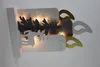 A decorative LED candle silhouette with a reindeer and tree motif, illuminated from within. Produktbild-Vorschau