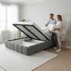 A couple is putting pillows and bedding into an open storage bed in a bedroom. Produktbild-Vorschau