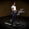 A woman is using a treadmill with a laptop desk attached, working while exercising. Podgląd zdjęcia produktu