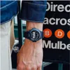 A person wearing a dark blue G-Shock watch on their wrist, with a black background featuring white text and orange circles with letters. Náhľad obrázku produktu