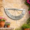 A sundial mounted on a stone wall, with potted plants in the foreground and greenery and pink flowers in the background. Produktbild-Vorschau