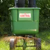 A person is using a green fertilizer spreader in a grassy area. Anteprima dell’immagine prodotto