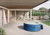 An inflatable hot tub is set up on a patio next to a modern house with an open kitchen visible through sliding glass doors. Produktbild-Vorschau