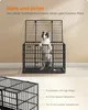 A dog is standing in a black metal dog crate with the top open. The background is a plain wall and floor. Produktbild-Vorschau