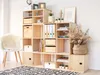 A modular wooden cube shelving unit filled with various items, placed in a room with a chair and rug. Produktbild-Vorschau