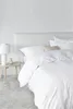 A neatly made bed with white bedding in a minimalist bedroom setting. Produktbild-Vorschau