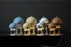 A collection of Hoptimist lamps in various sizes and colors, displayed on a dark surface against a dark background. Produktbild-Vorschau