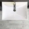 A top-down view of a white ceramic sink with a chrome faucet, set against a tiled floor. Produktbild-Vorschau