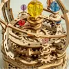 A close-up view of a wooden mechanical model of a solar system, with colorful crystal spheres representing planets. Voir les images du produit