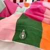 A close-up of a colorful duvet cover with a clear button and thread. Voir les images du produit