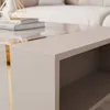 Close-up of a modern coffee table with a beige surface and gold accents. Produktbild-Vorschau