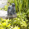 A garden fountain with two seal statues spraying water, surrounded by lush green plants. Produktbild-Vorschau