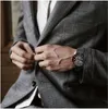 A man in a suit is buttoning his jacket, showing off his watch. Produktbild-Vorschau