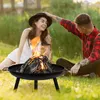 A couple sitting on grass around a fire pit. Produktbild-Vorschau